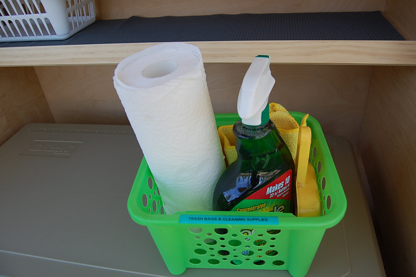 RV rental cleaning supplies: paper towels, spray cleaner, and rags in labeled green basket. Ready for spotless travel.