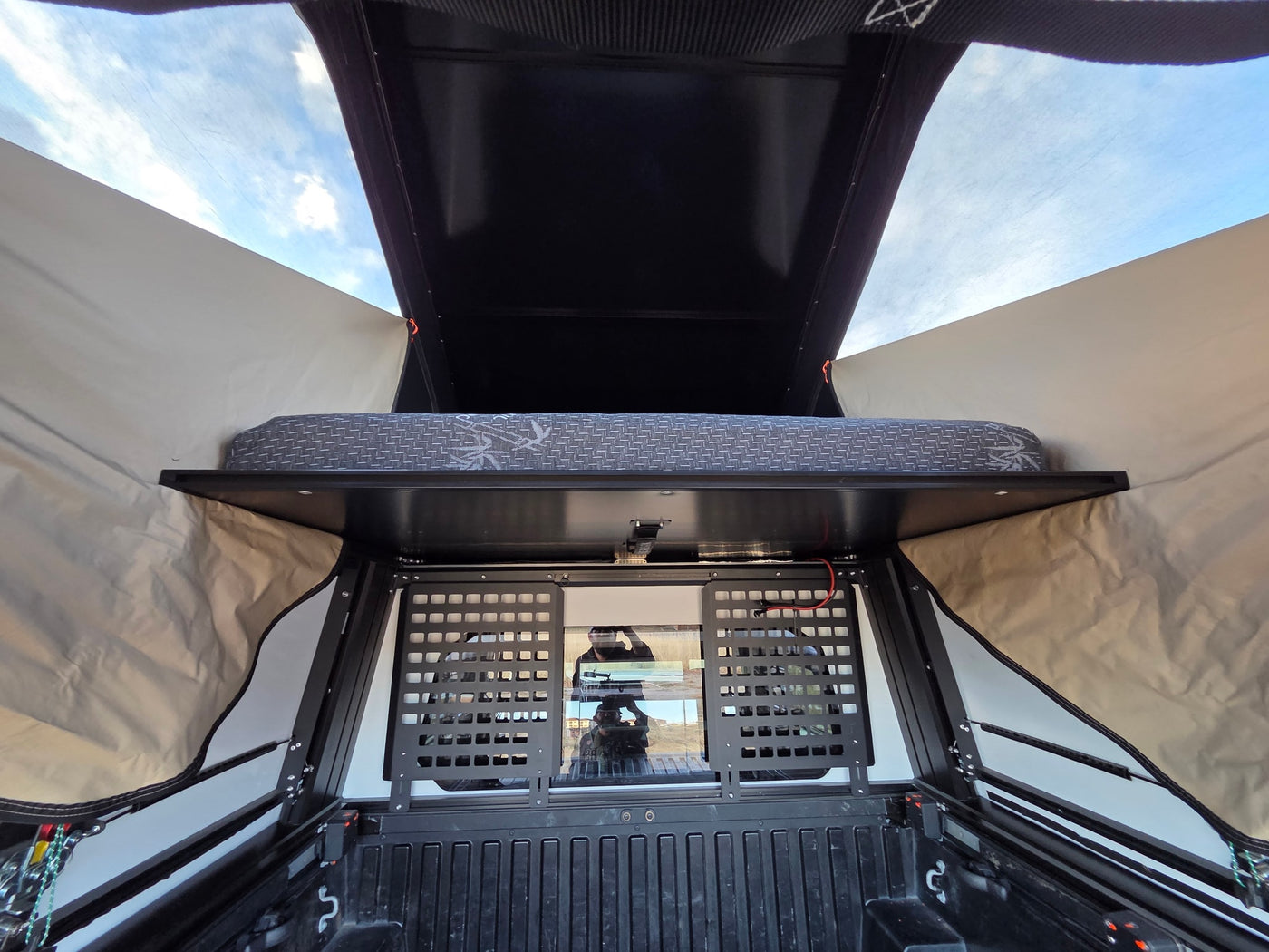 Inside a truck bed camper, showing the mattress and cargo grid. Perfect for your next RV rental adventure! — photo 7