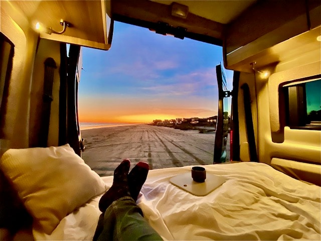 parked on a sandy beach at sunset beside the ocean. Ideal RV rental.|Dark camper van on a sandy beach at sunset. Vibrant sky & ocean; perfect RV rental for beach adventures.|Inside a comfortable RV rental