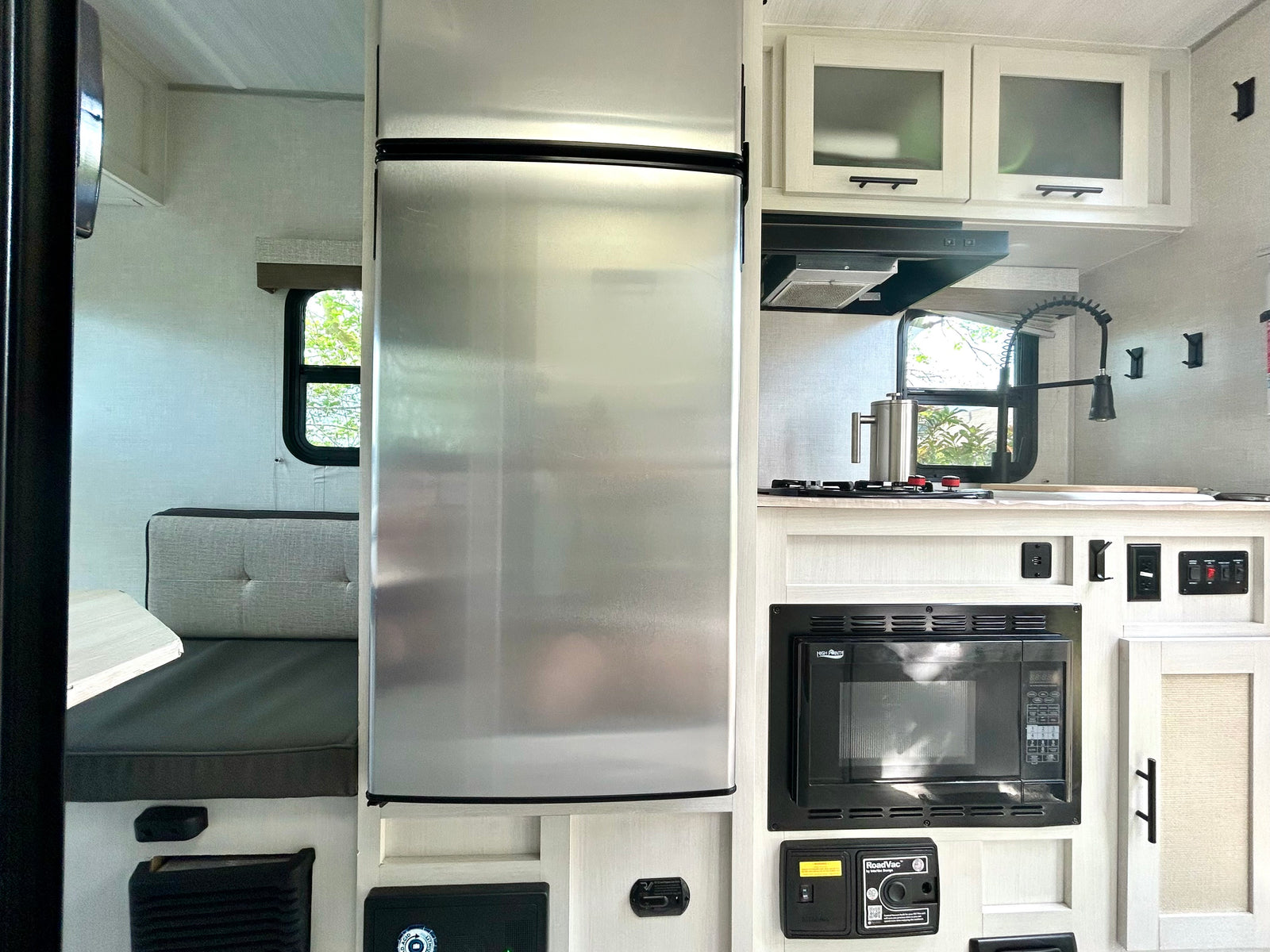 This RV rental's bright interior features a full kitchen with a large stainless steel fridge, microwave, gas range, and a dinette.