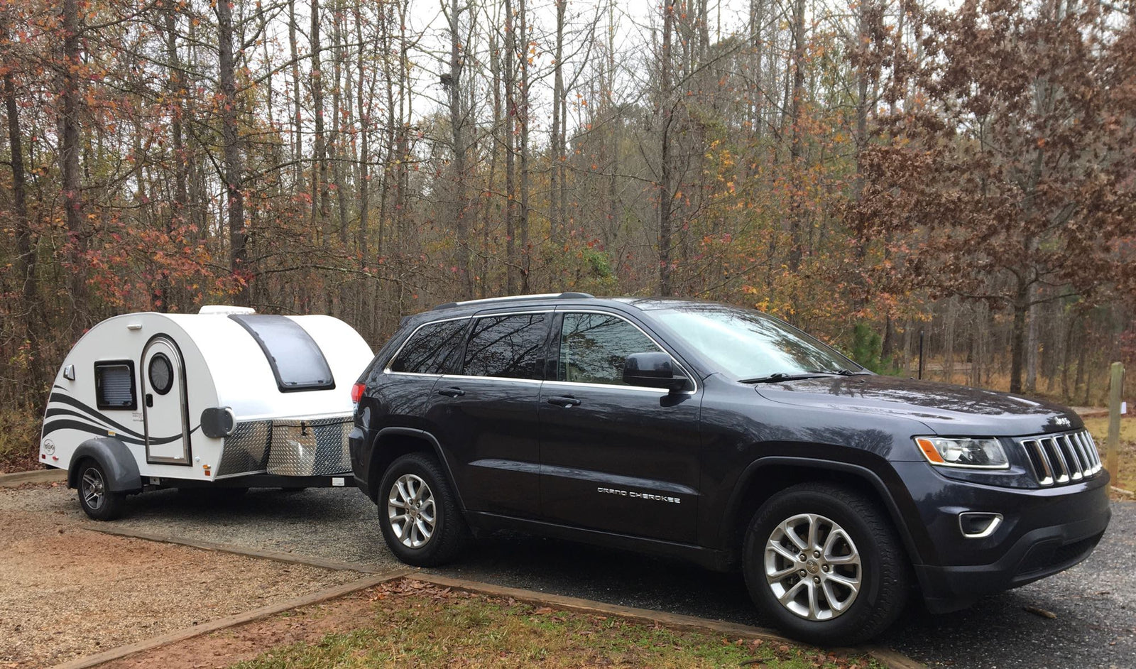 Jeep Grand Cherokee with a teardrop RV rental, ideal for outdoor camping and travel adventures in nature.