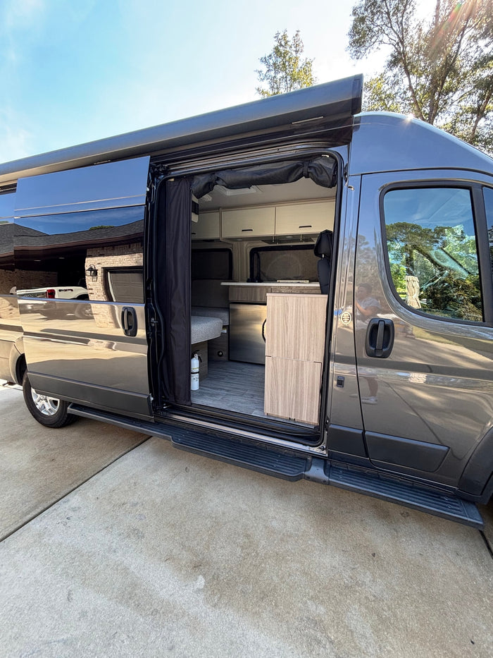 ready for adventure under a blue sky.|Spacious gray RV rental camper van with open door revealing cozy interior