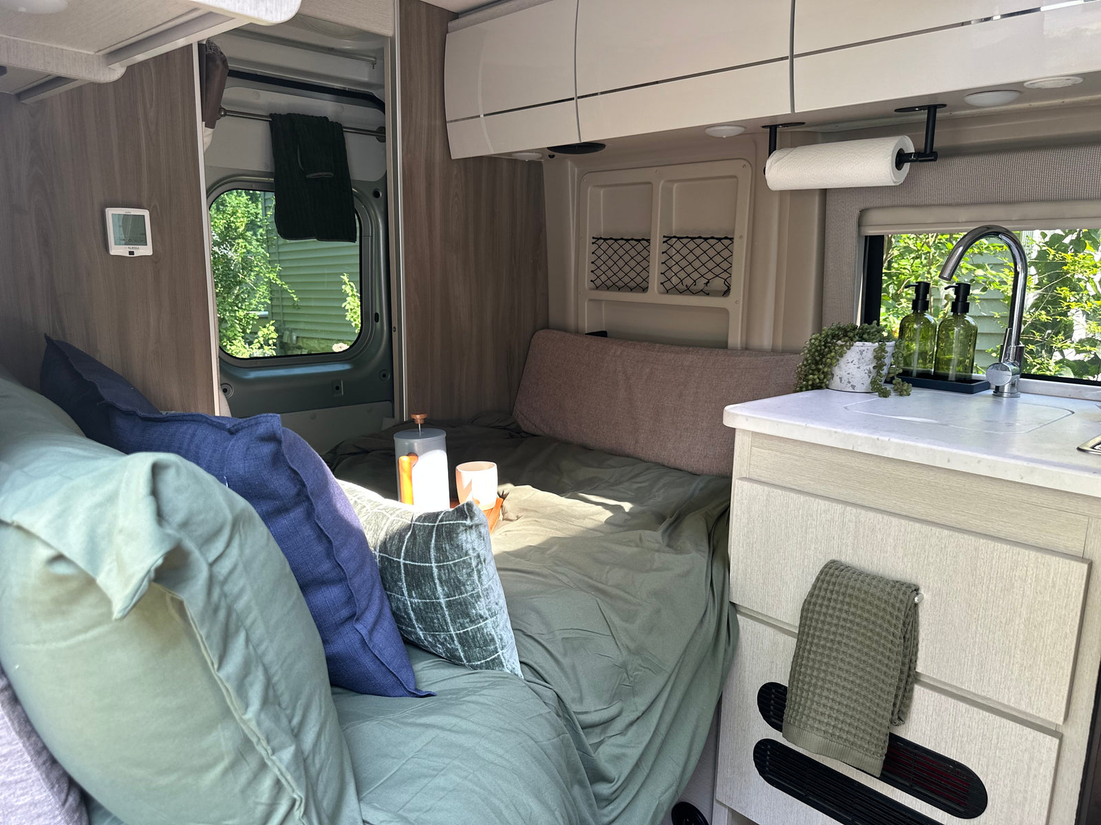 Enjoy this inviting RV rental interior, featuring a cozy bed, compact kitchen, and travel essentials like coffee.