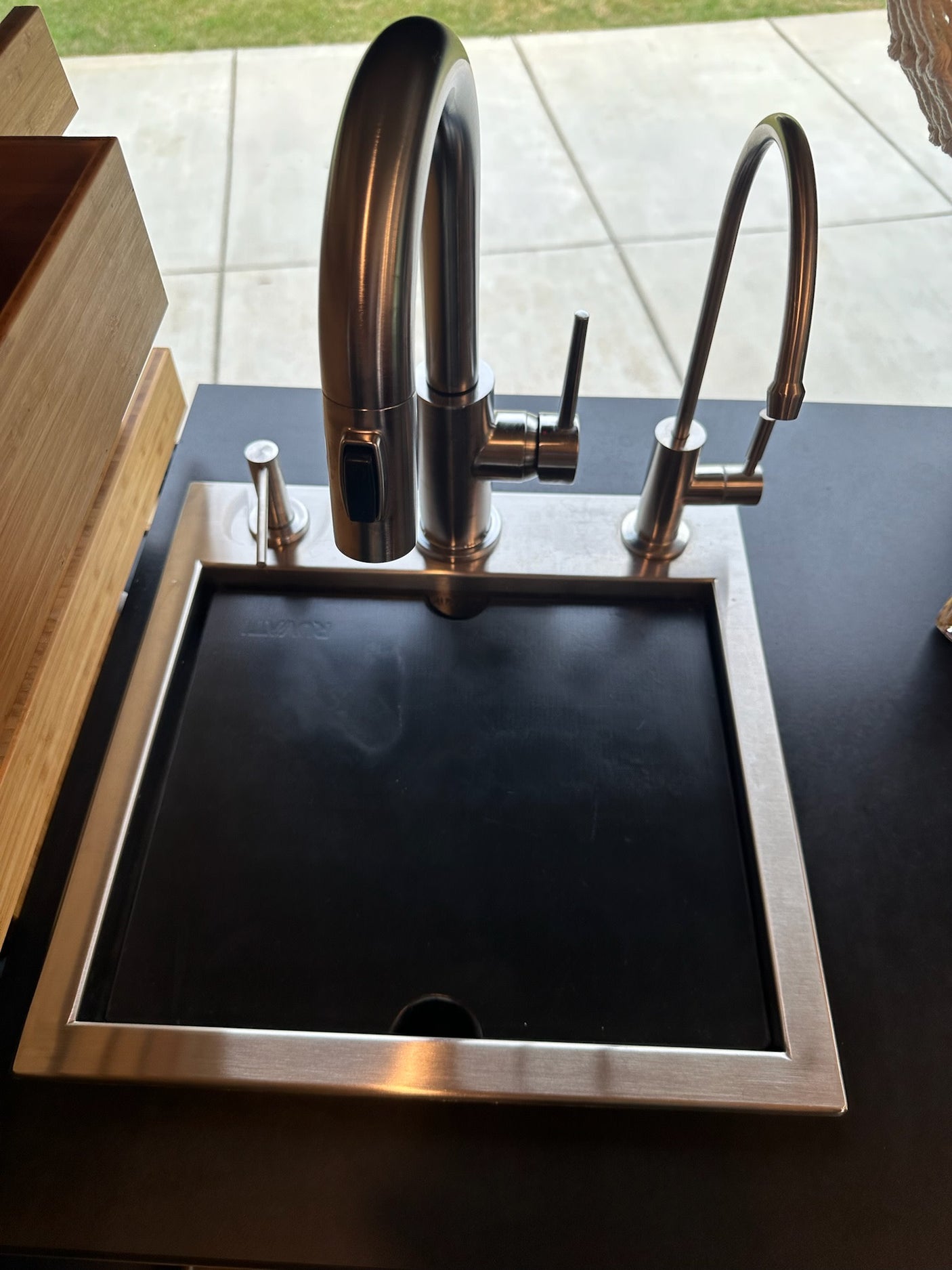 Sleek stainless steel sink with main pull-down faucet, filter, and soap dispenser on dark counter, perfect for RV rental.