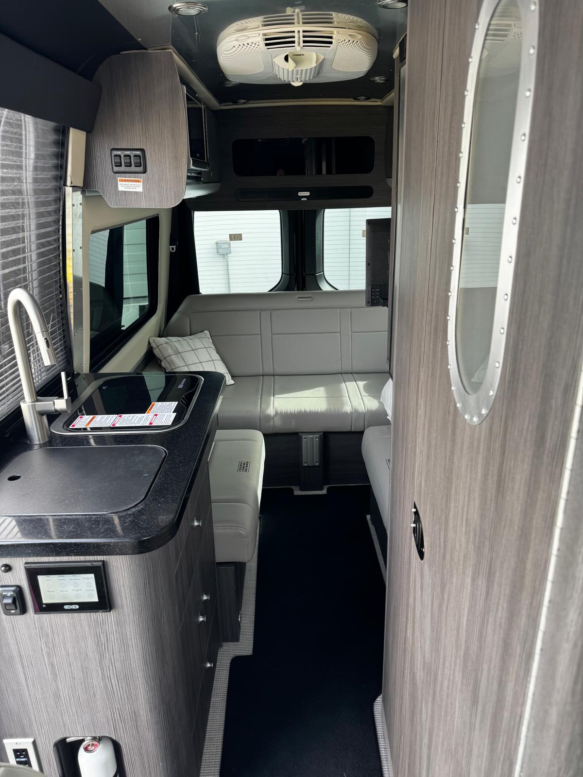 and another RV at a gravel campsite.|Inside this sleek black rv rental: warm lights