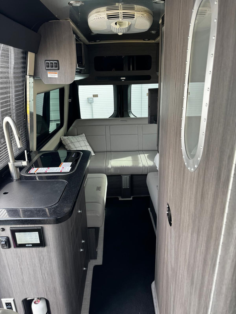 and another RV at a gravel campsite.|Inside this sleek black rv rental: warm lights
