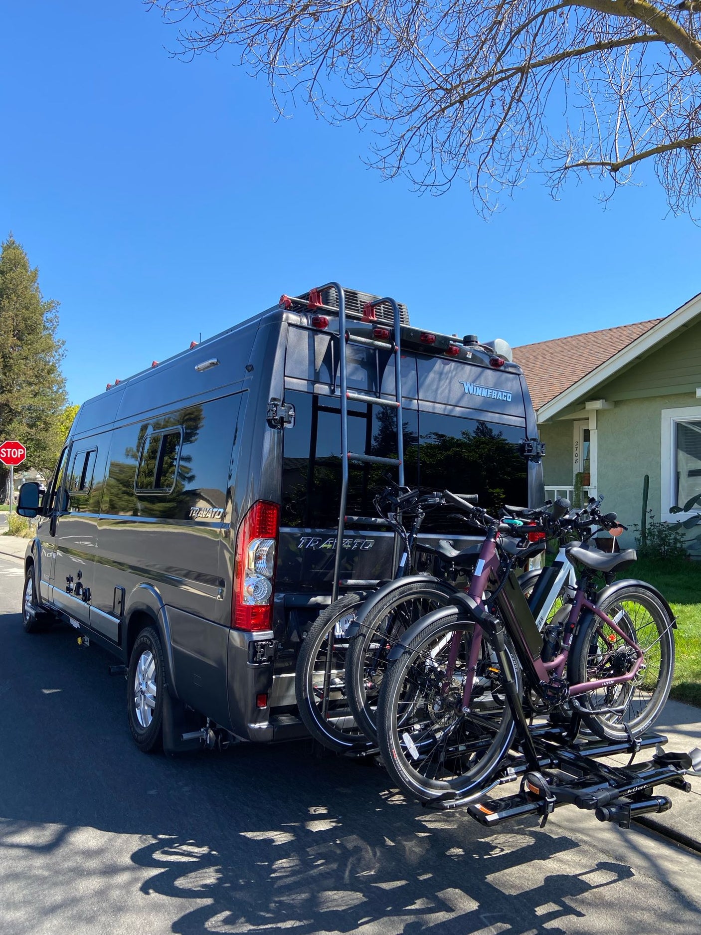 Stylish gray RV rental camper van with a rear bike rack holding two electric bikes, ready for an outdoor getaway.