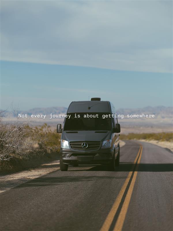 Explore with an rv rental! A camper van is parked on a desert road, mountains in the distance, perfect for your next road trip adventure.