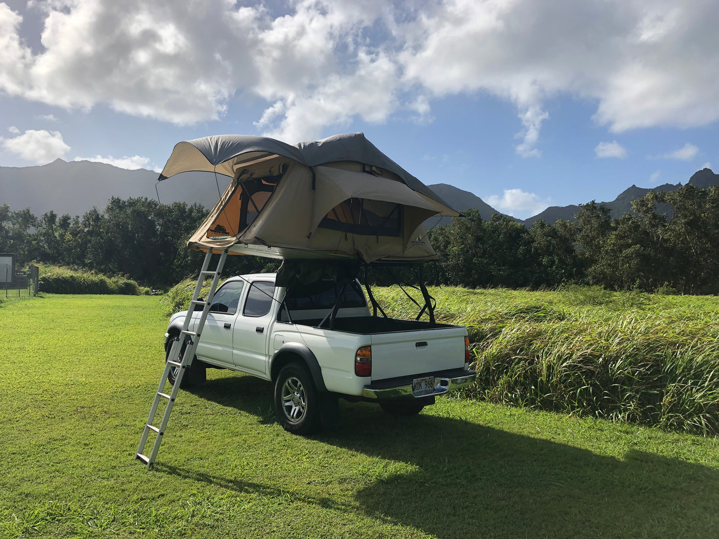 White pickup truck with a rooftop tent, an ideal RV rental for your outdoor mountain adventure.