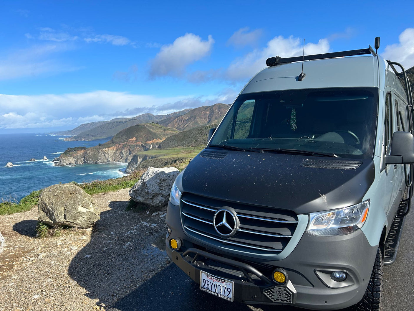 Custom Mercedes Sprinter rv rental parked at a scenic coastal overlook with ocean and mountain views.