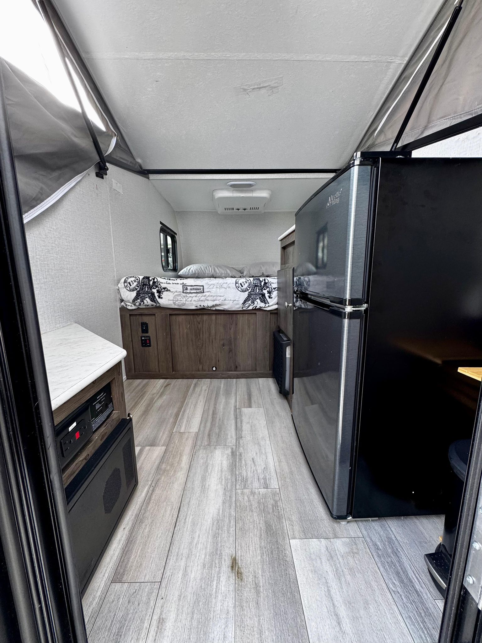 sits on a driveway under cloudy skies.|This rv rental setup features a gray Viking pop-up camping trailer and a Jeep Gladiator
