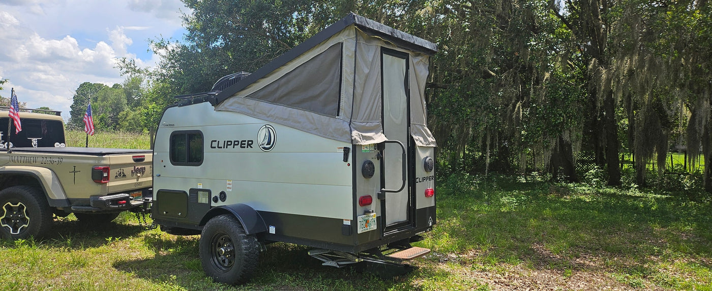 Tan Jeep Gladiator tows an open Clipper pop-up camper. Perfect RV rental for rustic adventures under mossy trees. — photo 6