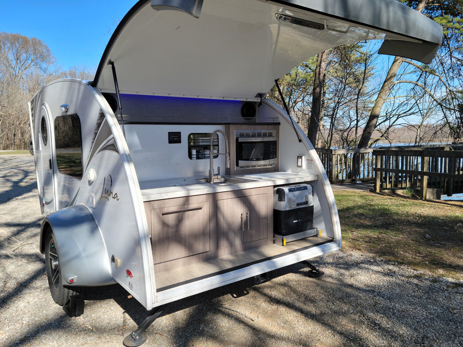Explore with this Luna teardrop RV rental! Its open rear galley kitchen, with sink, microwave, & cooler, is lakeside ready.