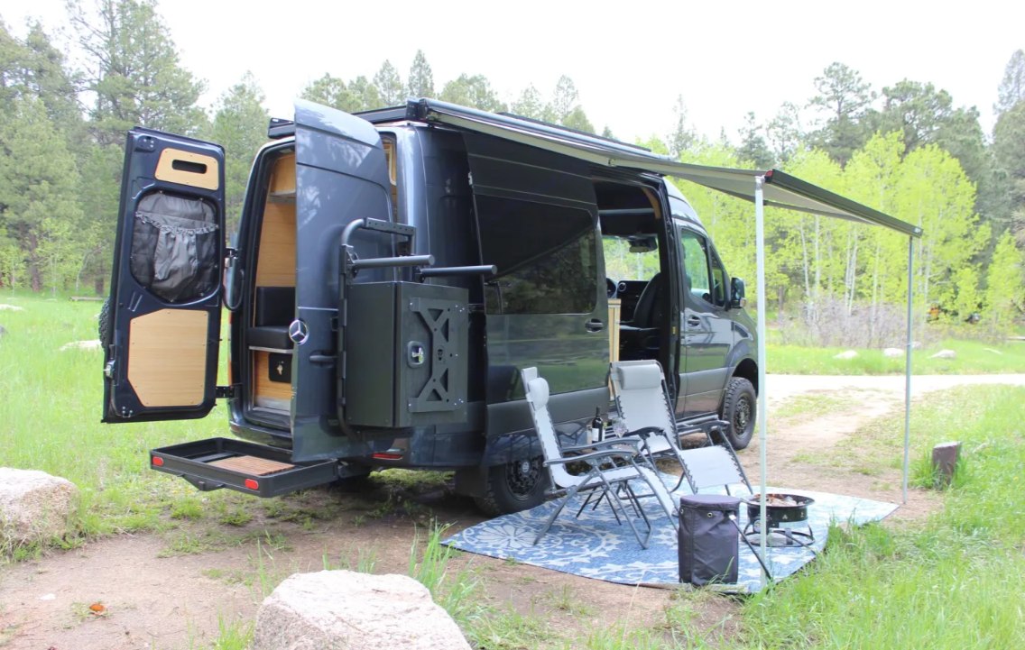 **RV rental** van parked with an extended awning, chairs, and fire pit for a cozy outdoor camping setup. — photo 6