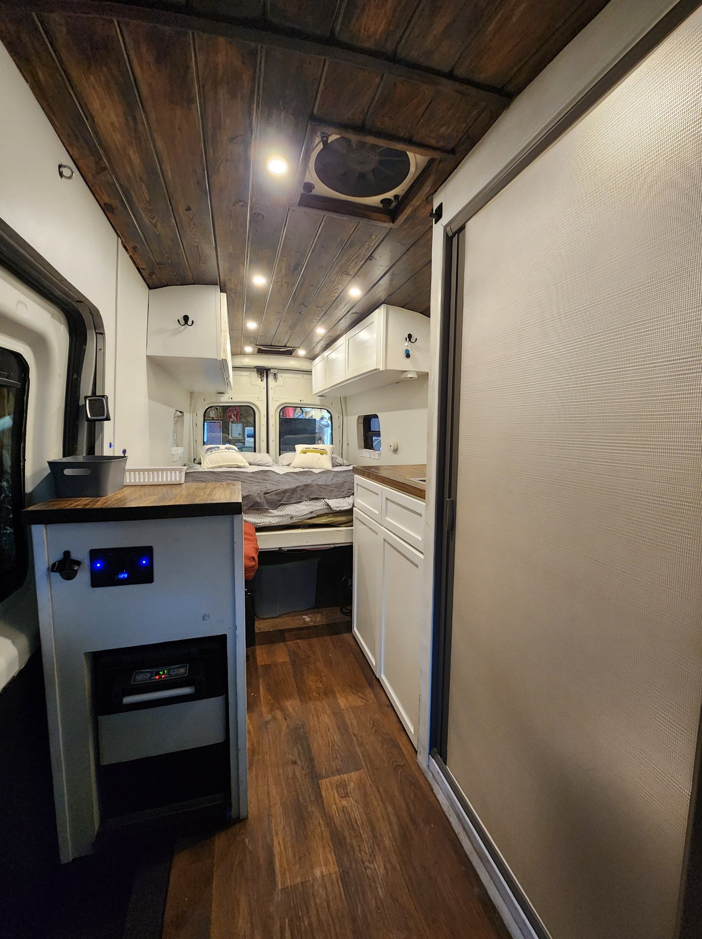 An RV rental interior showcasing a wooden ceiling, comfy bed, kitchenette, and built-in cooler for your next trip.