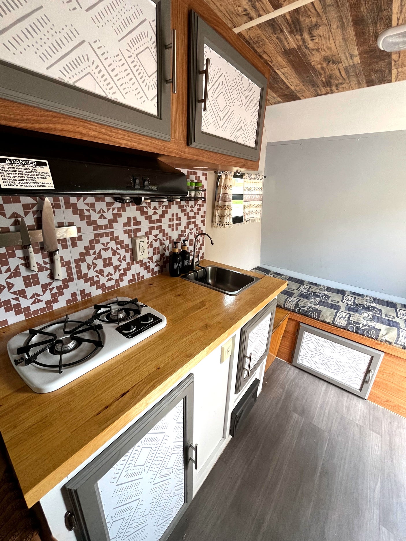 This cozy RV rental features a compact kitchen with patterned cabinets, wood counters, and built-in bench seating.