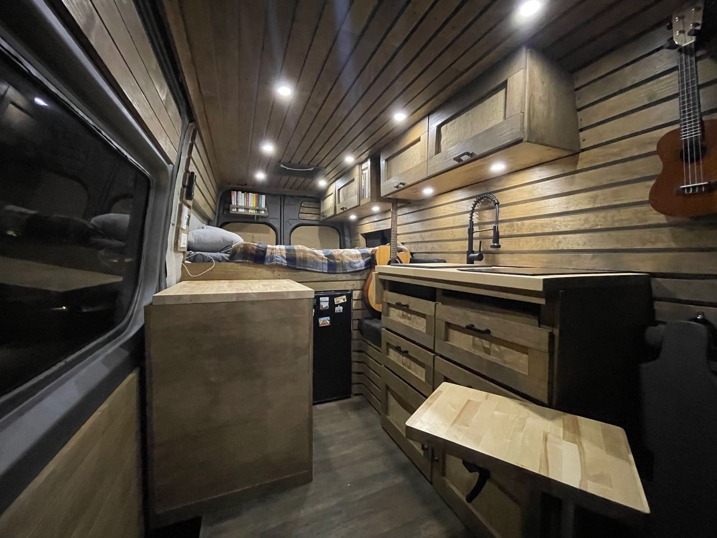 This RV rental showcases a warm wood-paneled interior with a built-in kitchen — photo 1