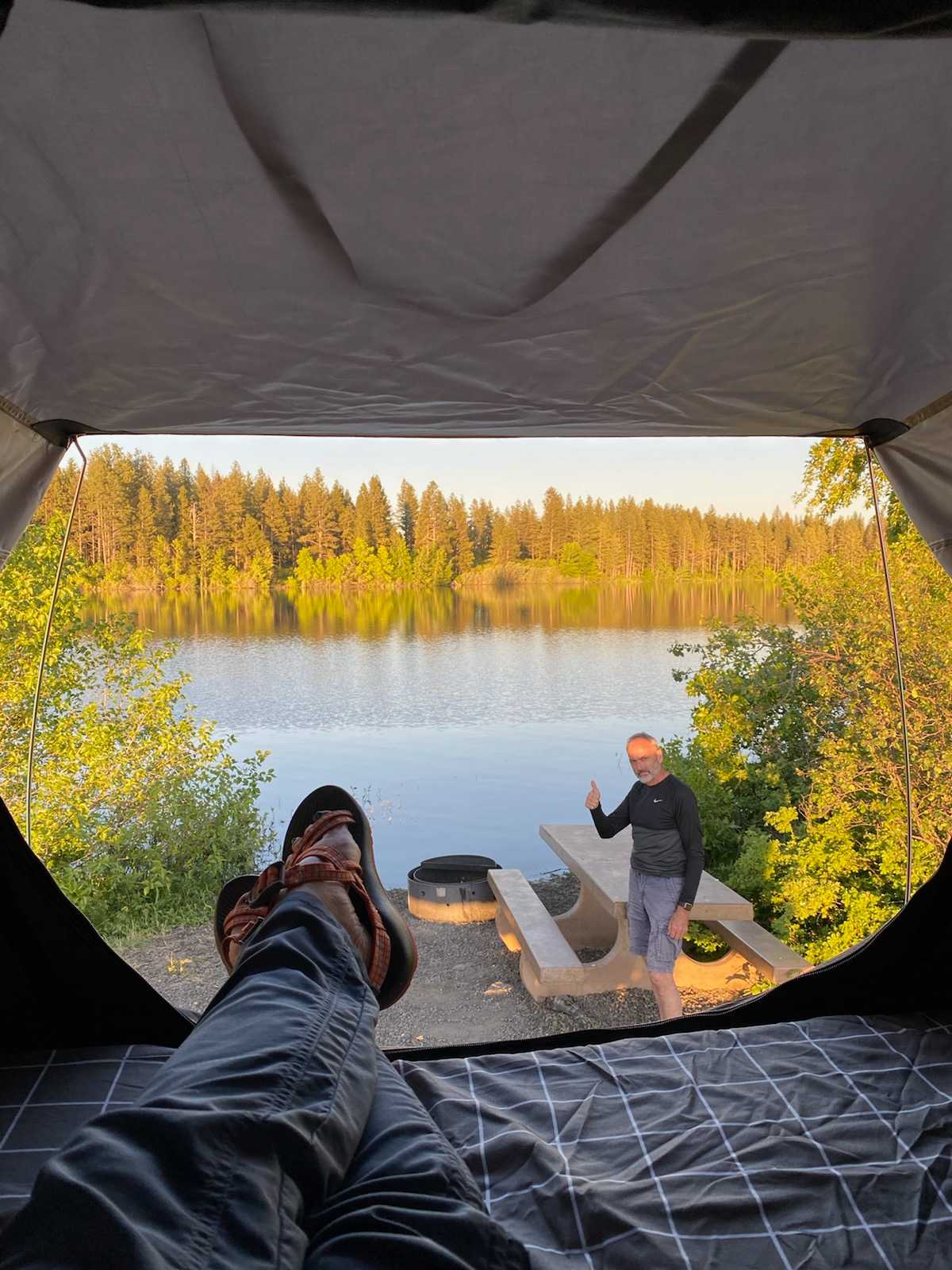 LED lights illuminate a storage pouch with a view of a green landscape and trees.|Scenic waterfront view from an RV rental rooftop tent. Enjoy peaceful camping by the river.|Comfortable