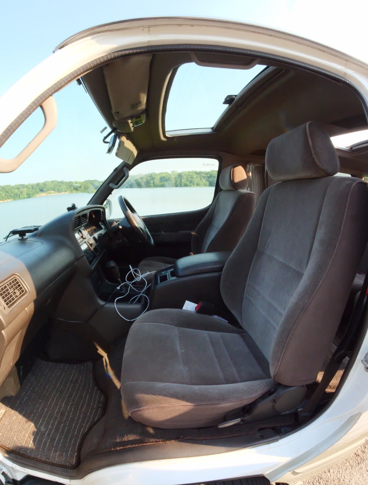 open doors on an Oregon road trip. Parked by a sunny lake.|Spacious van interior with convertible seating