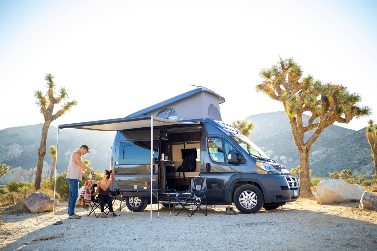 Serene desert camping with an RV rental. Couple enjoys coffee by their camper van — photo 1