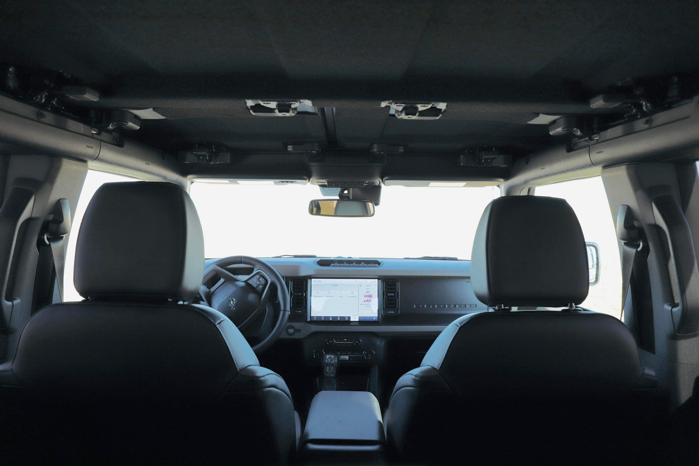 RV rental adventure: Ford Bronco interior from rear seats, featuring dashboard, steering wheel, and roof latches.