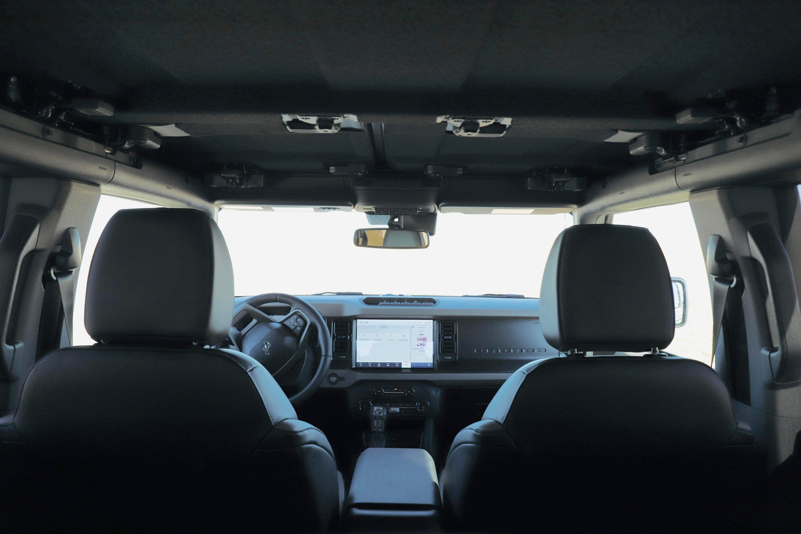 RV rental adventure: Ford Bronco interior from rear seats, featuring dashboard, steering wheel, and roof latches.