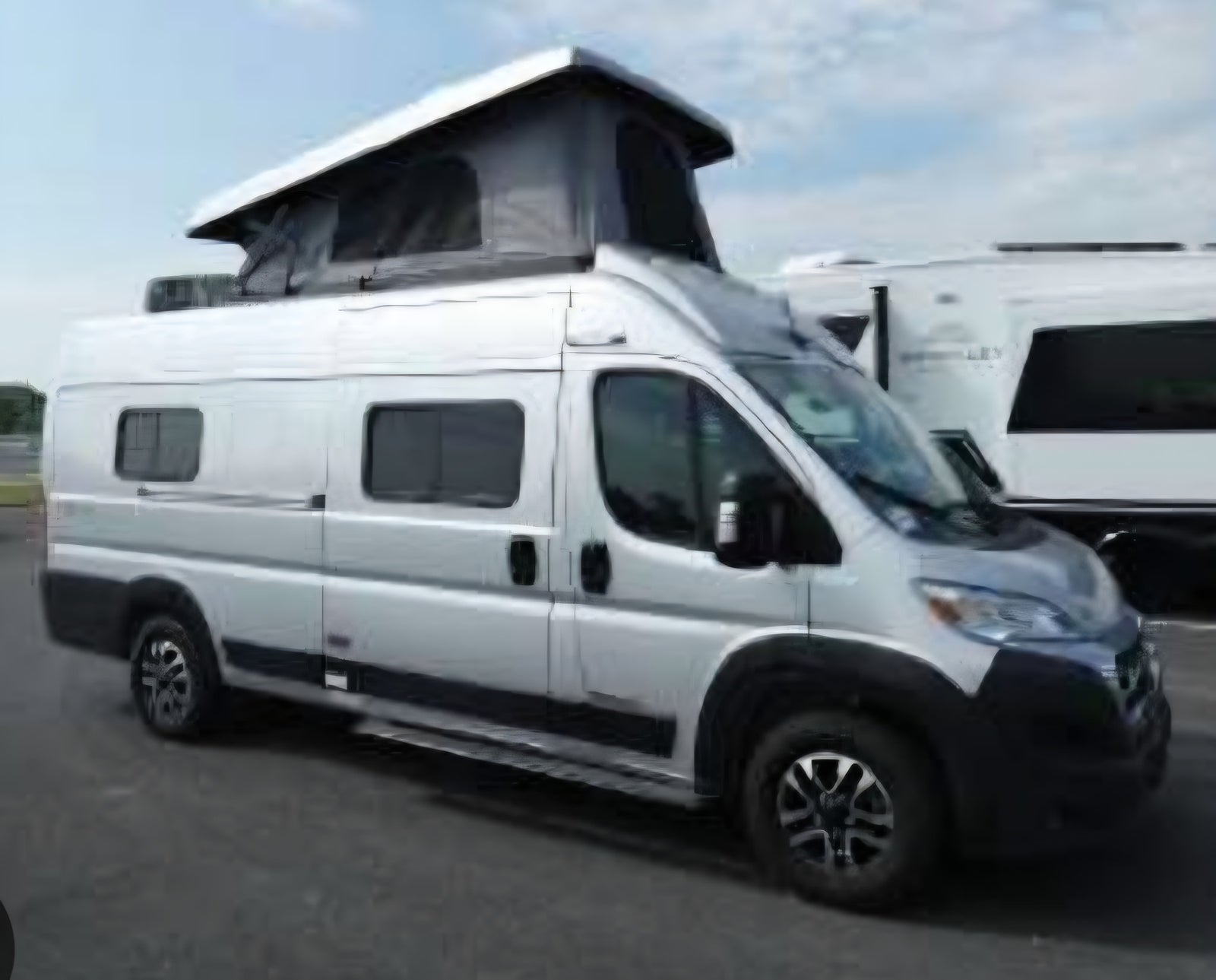 A silver camper van with its pop-top roof extended