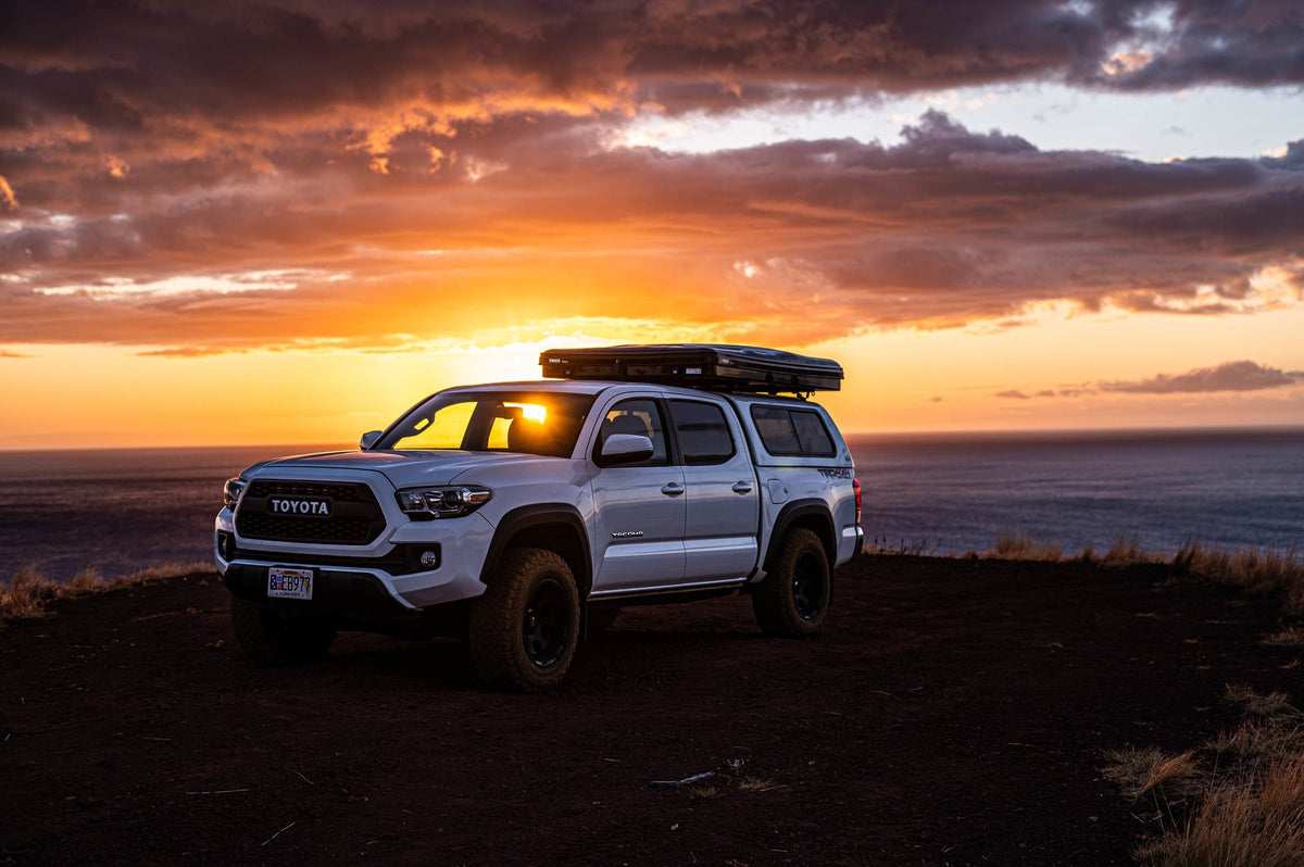 White Toyota Tacoma with rooftop tent overlooking the ocean at sunset. Perfect rv rental for overlanding adventures. — photo 3
