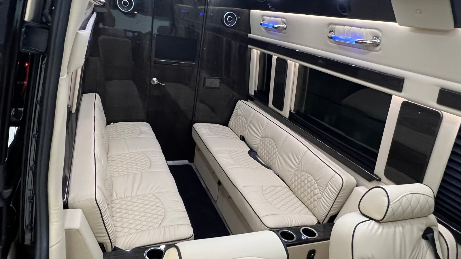 A plush **rv rental** interior showcases quilted cream benches, dark wood accents, and ambient lighting, offering luxurious travel comfort.