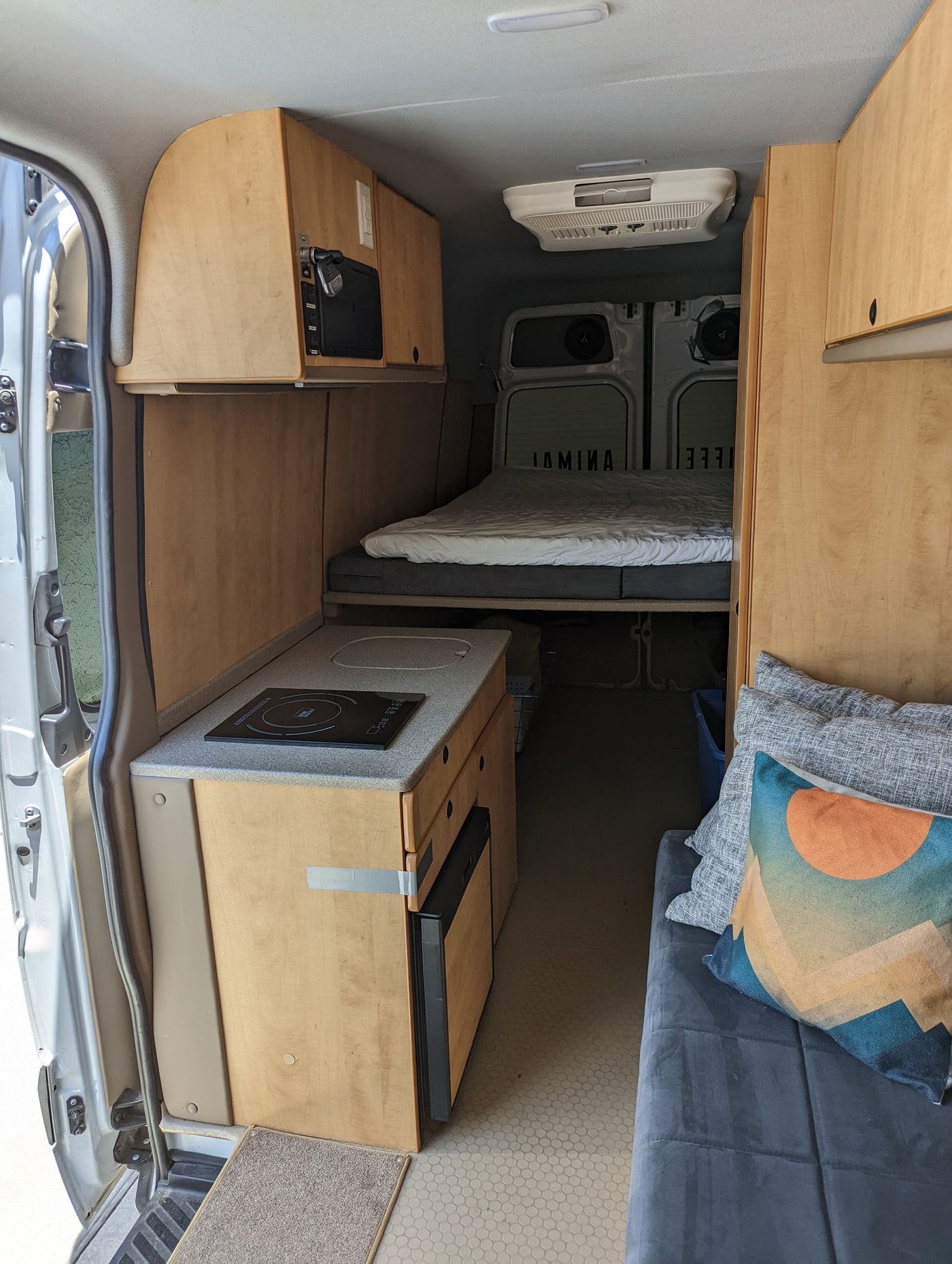 Explore this comfy RV rental camper van interior. Features a kitchen, bed, and cozy living area, perfect for road trips. — photo 19