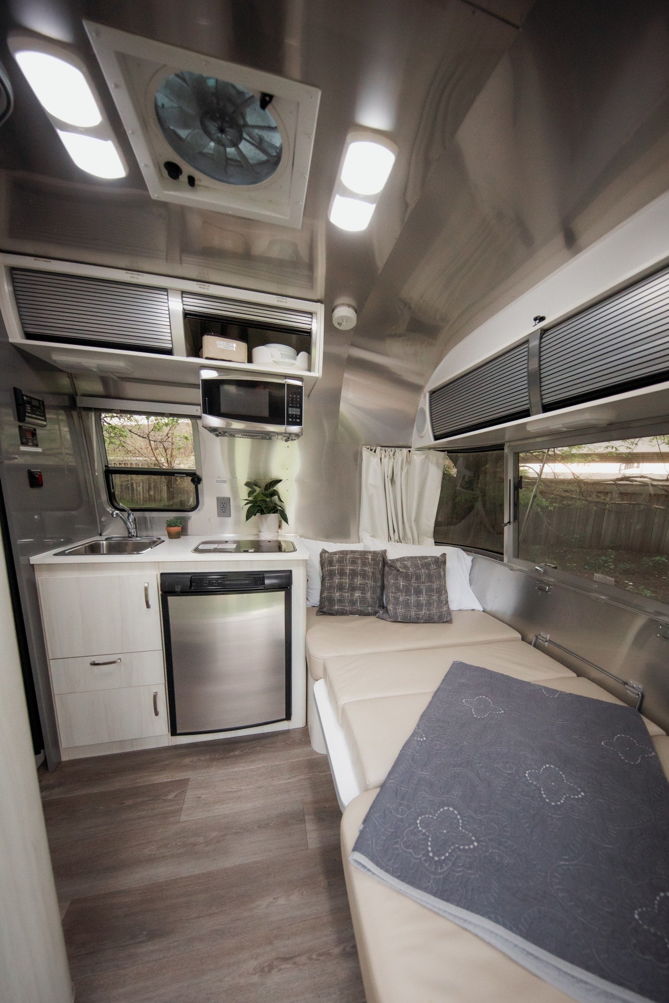 Inside this RV rental: a streamlined kitchen with fridge & microwave, plus a comfortable convertible bed. Ideal for road trips.