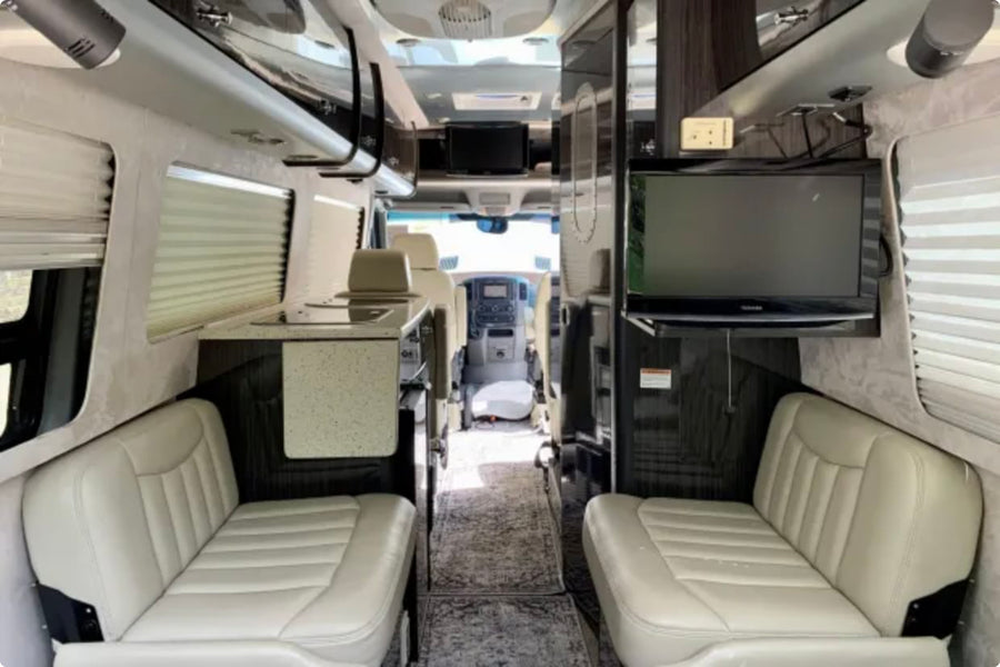 Spacious RV rental interior featuring comfortable seating, a compact kitchen, and TV for enjoyable travels.