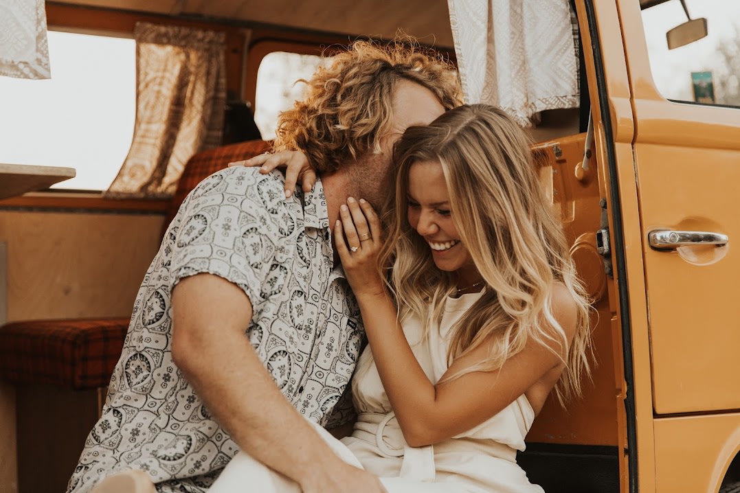 Happy couple enjoying their RV rental adventure inside a cozy camper van, laughing and embracing.