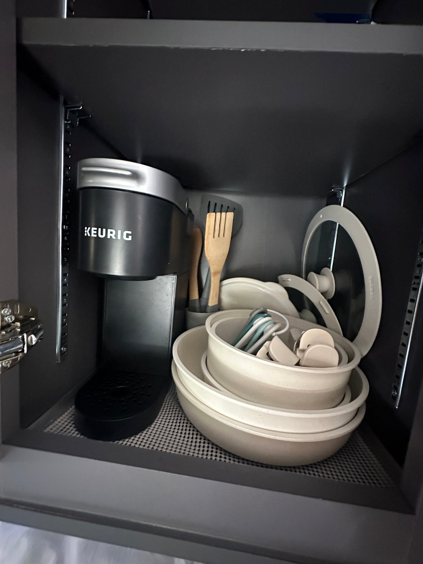Compact kitchen setup in an rv rental, featuring a Keurig coffee maker and stacked kitchenware in a dark cupboard.