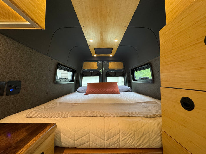 with a lake under a bright blue sky.|Relaxing RV rental interior showcasing a large bed