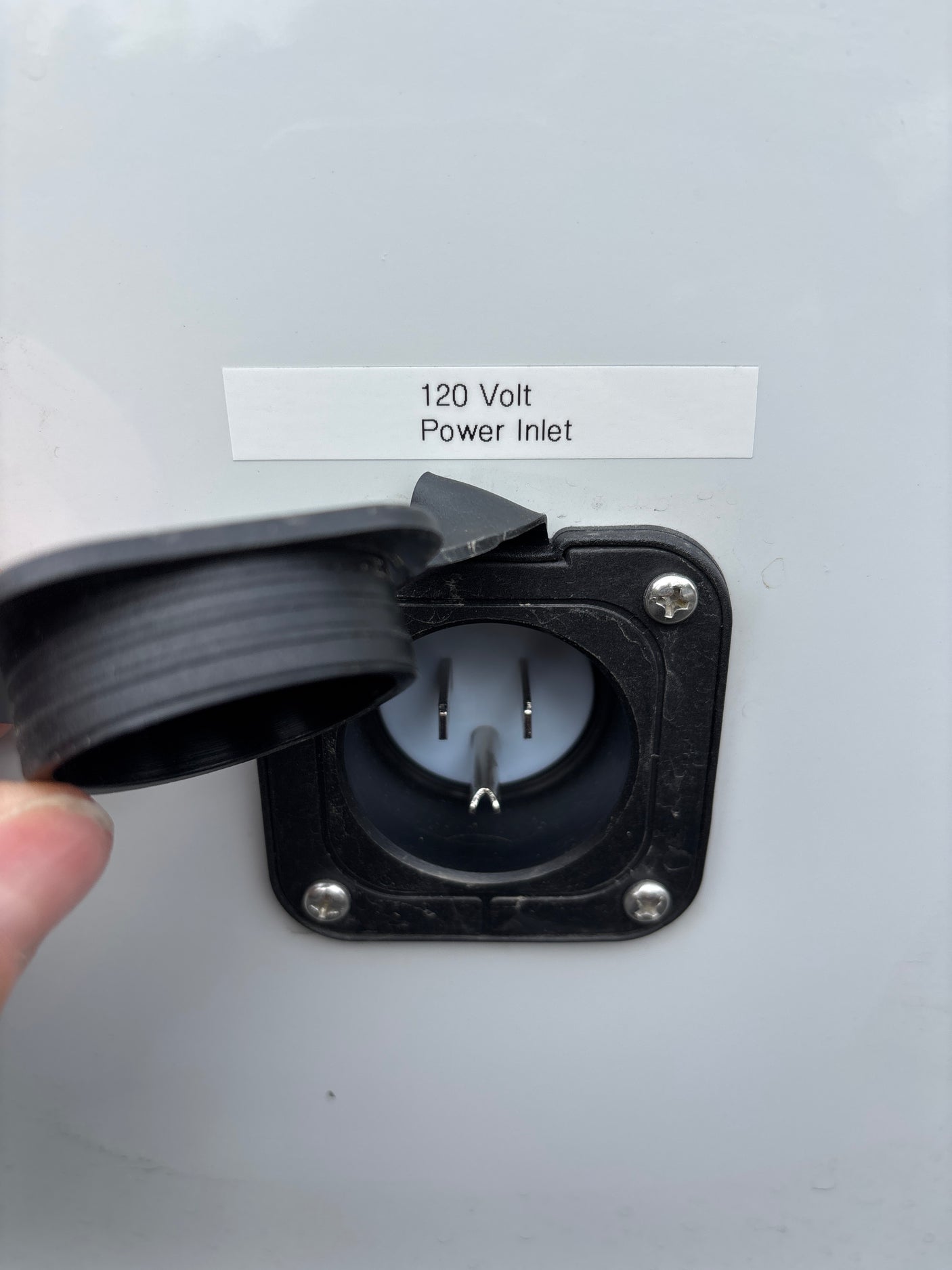 This image shows an open 120 Volt power inlet on an RV rental, ready for shore power connection. The electrical receptacle's cap is open.