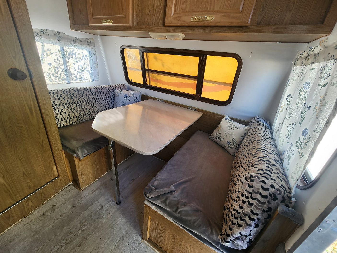 Cozy RV rental dinette area with table, patterned cushions, and warm lighting. Perfect for road trip meals.