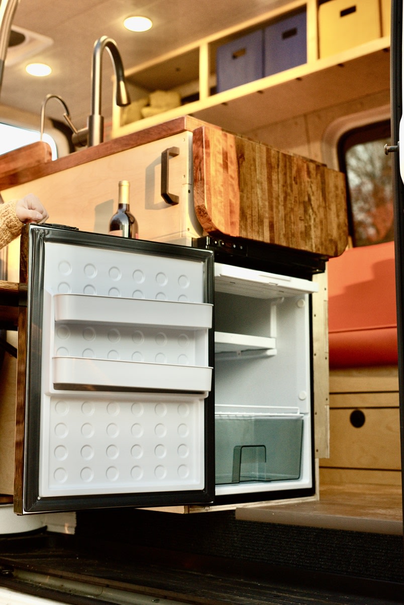 and rear windows revealing a road. Van life comfort.|Smiling woman relaxes in a cozy RV rental camper van at night