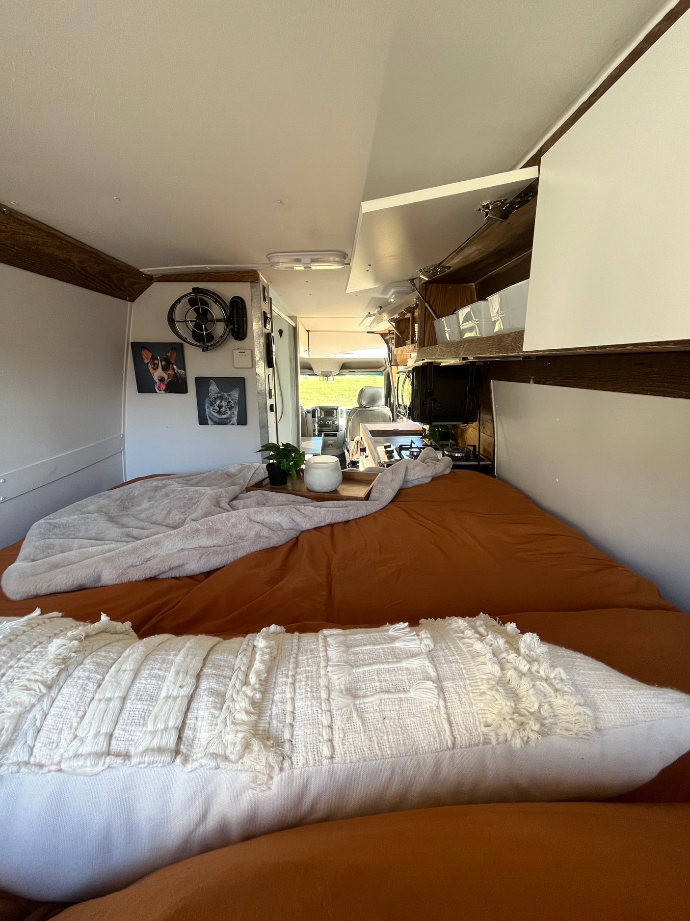 Cozy RV rental interior with a comfy bed, kitchen, and personalized pet portraits, offering a perfect travel escape.