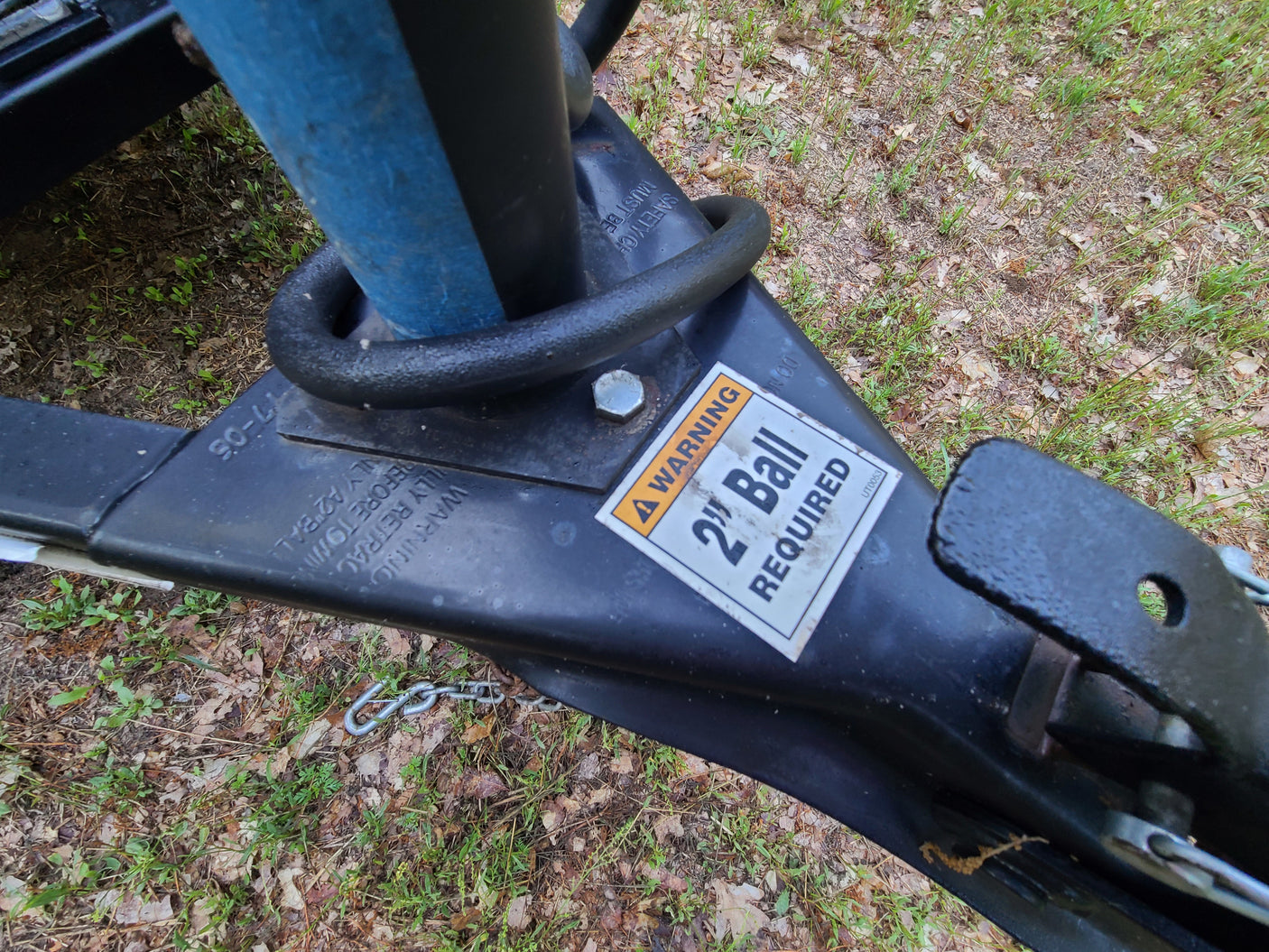 Close-up of an RV rental trailer hitch, showing a "2" Ball REQUIRED" warning sticker and safety chains.