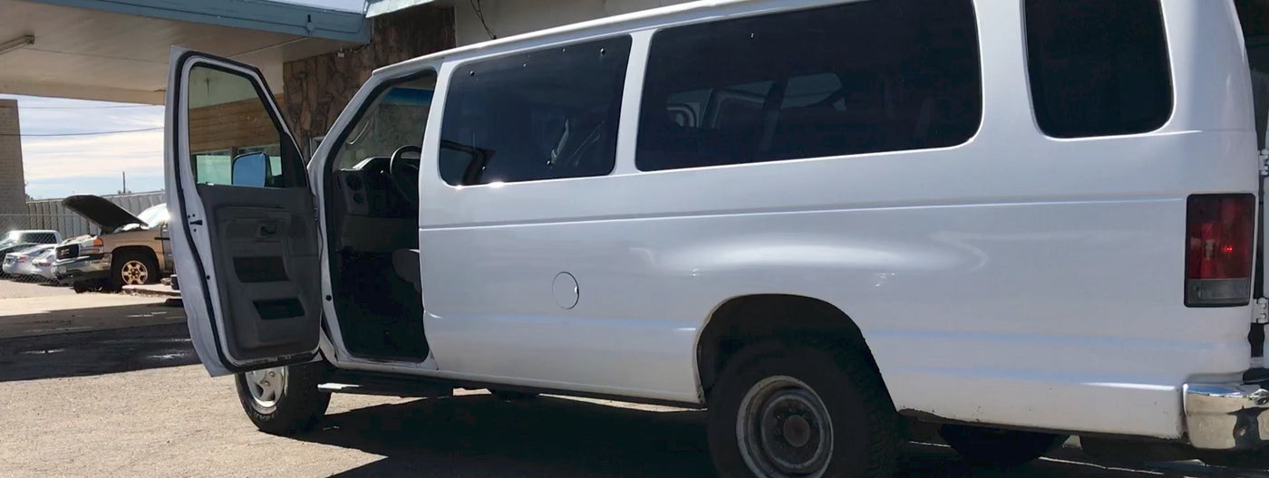 with other vans and puddles.|Front of white Ford van with open doors in a lot. Find versatile transport for trips — photo 3