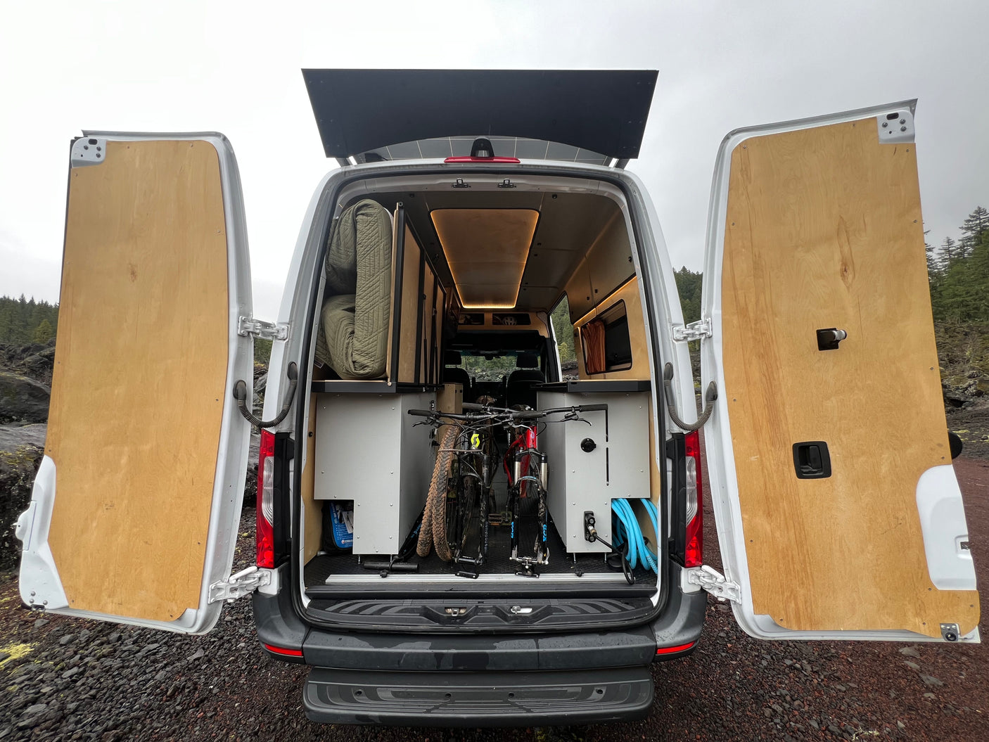 Rear view of a customized RV rental camper van, showing two mountain bikes & built-in storage. Ideal for adventures.