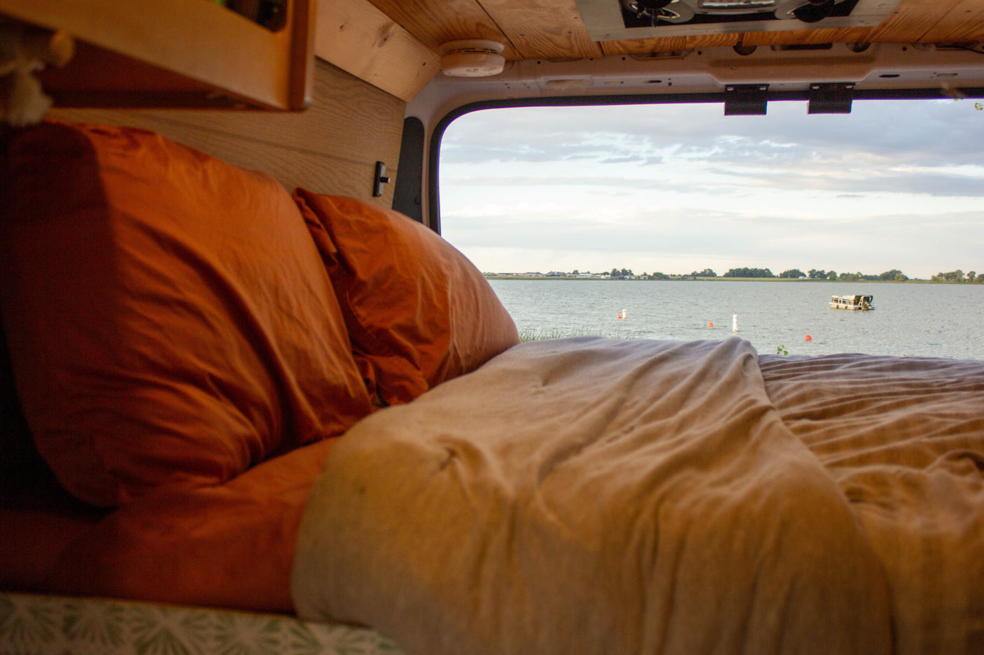 Enjoy serene lake views from your comfortable RV rental bed, offering a cozy escape in a camper van.