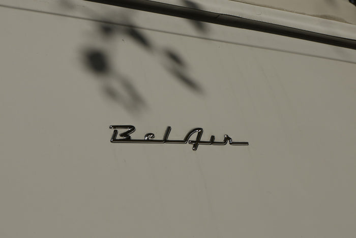 with a chrome winged hood ornament & wipers. Trees reflect in the windshield.|Sleek chrome hood ornament