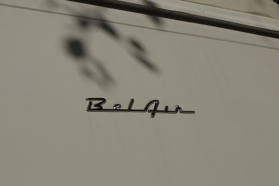 with a chrome winged hood ornament & wipers. Trees reflect in the windshield.|Sleek chrome hood ornament