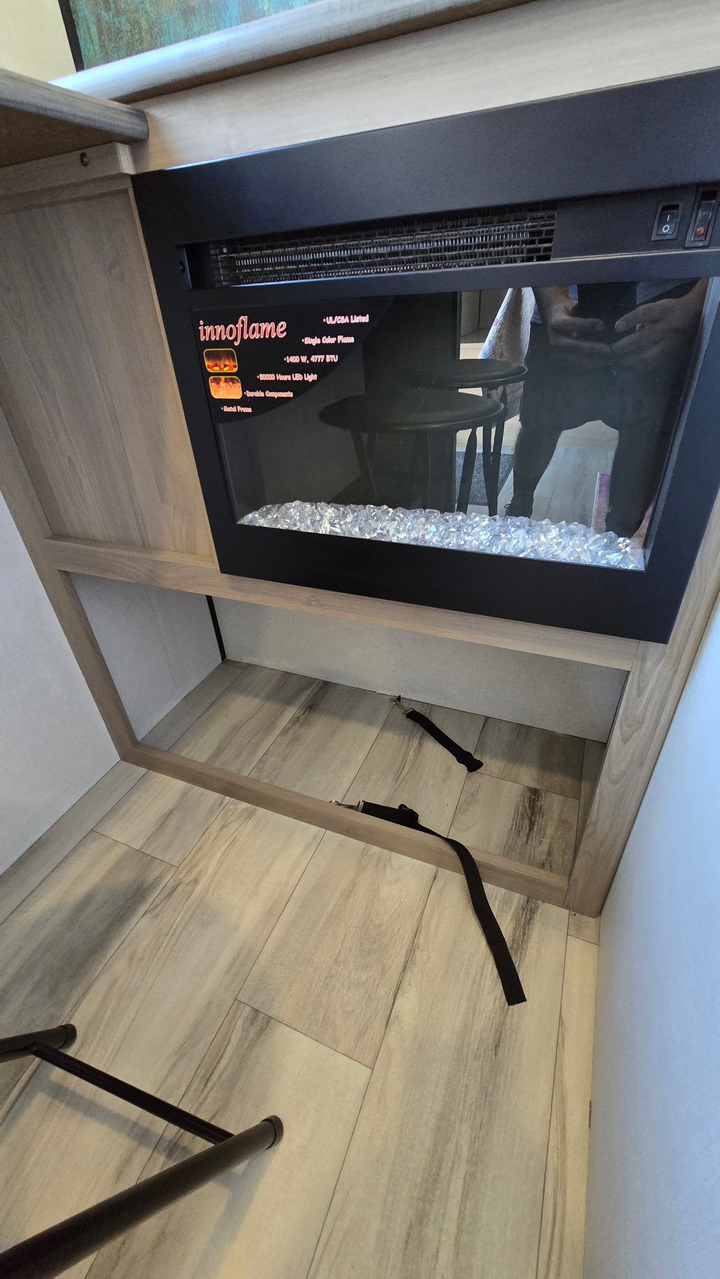 RV rental interior: cozy Innoflame electric fireplace with crystal media, built into wood cabinetry, offering warmth and storage.