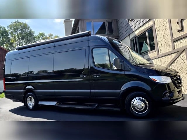 reflecting blue skies and trees. Chrome wheels & running boards.|RV rental luxury interior: two rows of cream quilted leather seating
