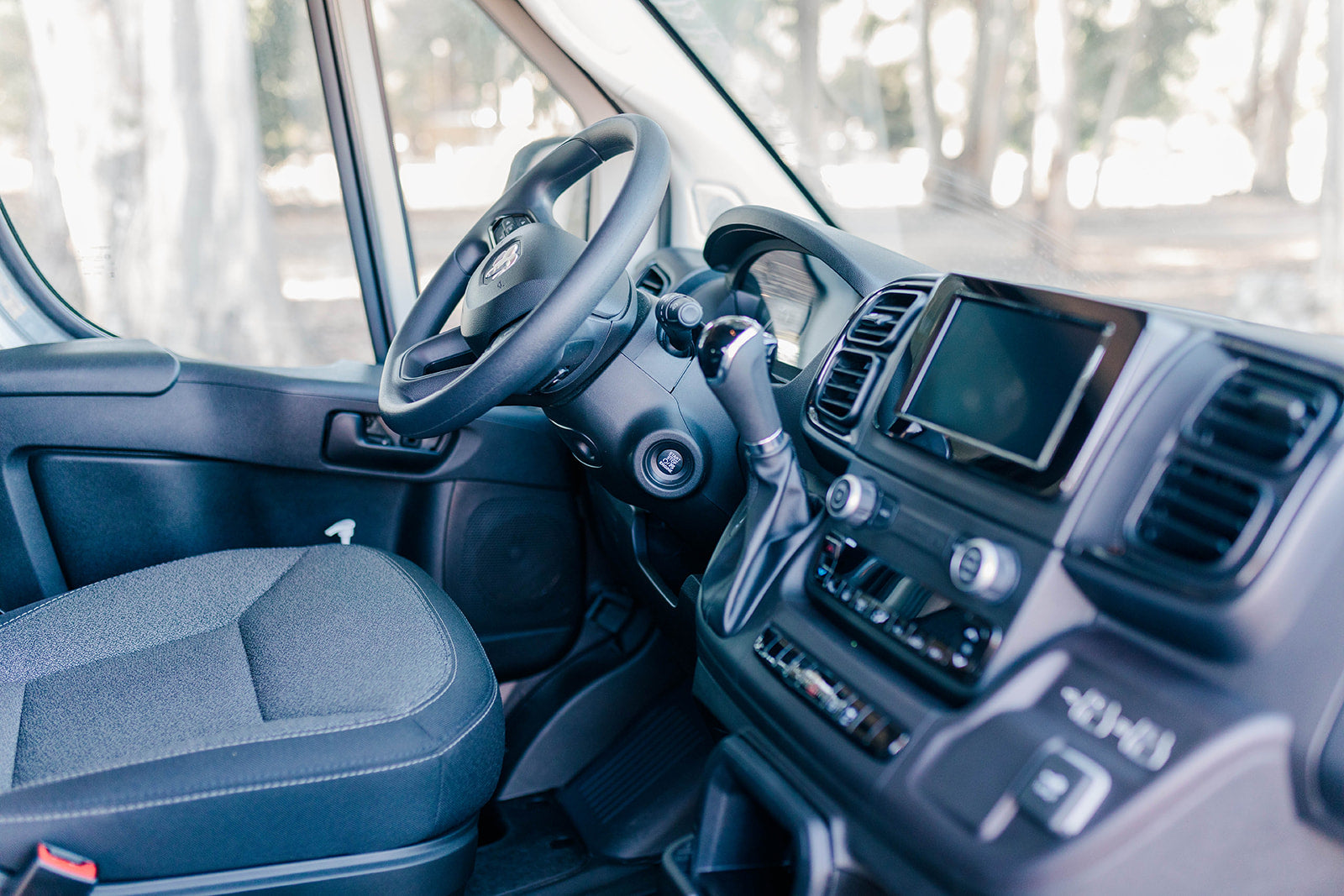 Explore the modern interior of an RV rental: driver's seat, steering wheel, and tech-equipped dashboard await your adventure.