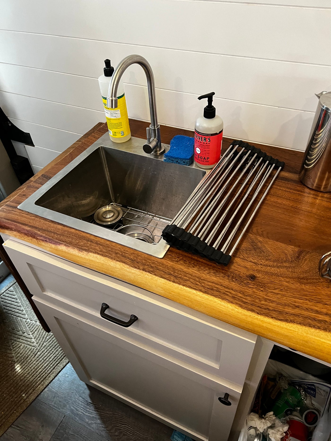 Inside an RV rental, a clean kitchen sink area with a wood counter, soap, and drying rack. — photo 8