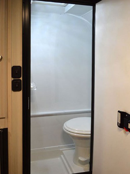 This rv rental features a compact white bathroom with a toilet and shower pan visible through the doorway.